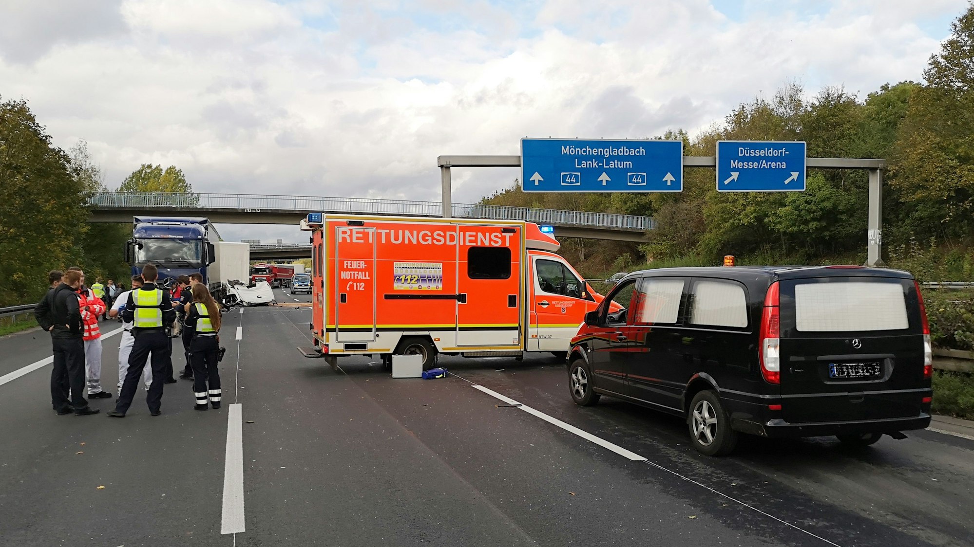 Polizisten und Rettungskräfte stehen neben einem Krankenwagen und einem Leichenwagen auf einer Fahrbahn der Autobahn A44.