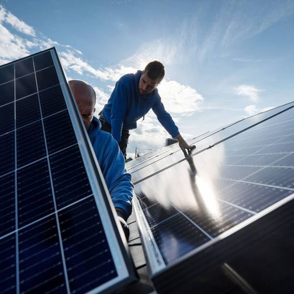 Arbeiter montieren Photovoltaikmodule auf dem Dach eines Wohnhauses.