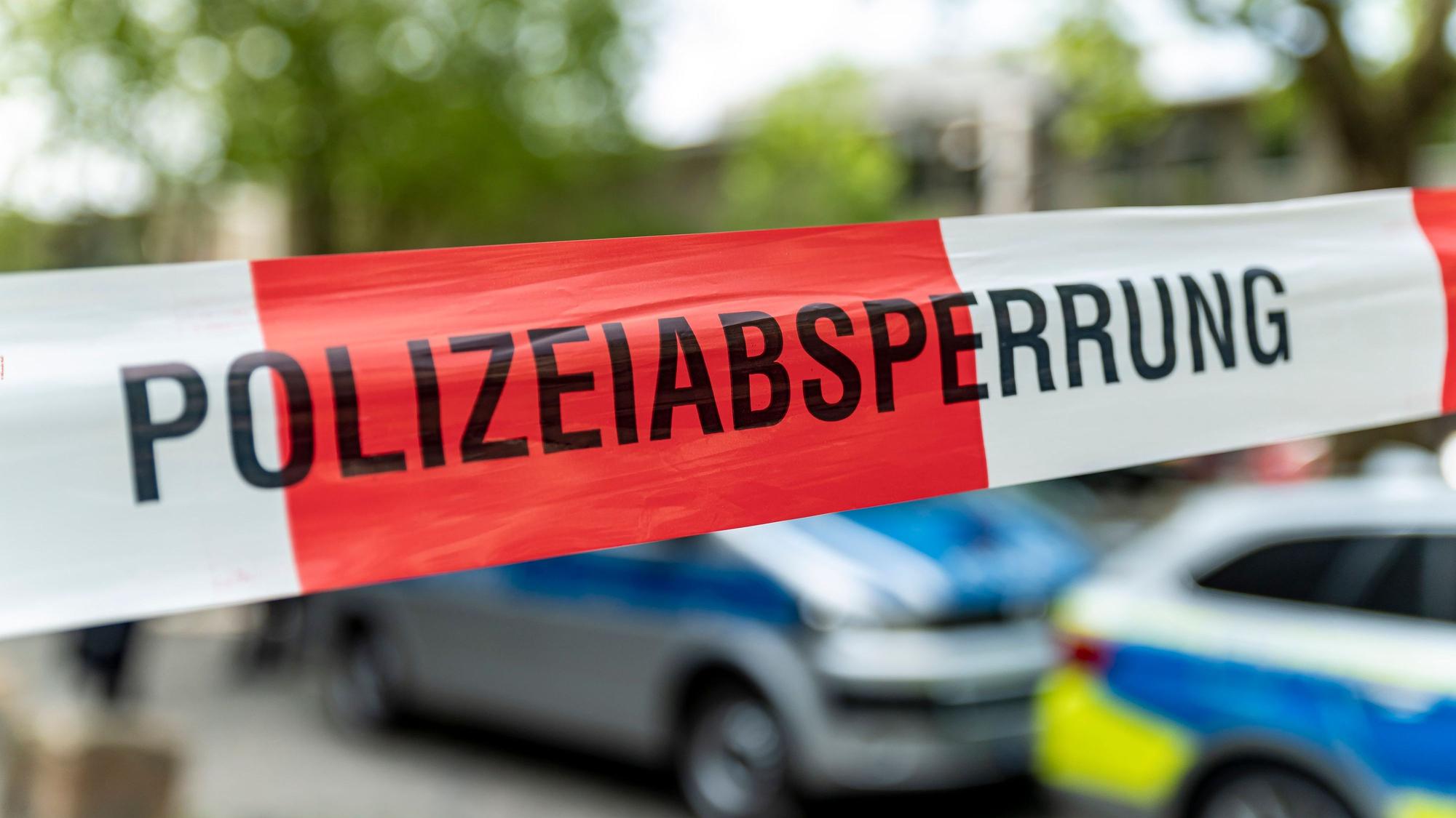 Ein mit Flatterband der Polizei abgesperrter Bereich mit Polizeiautos im Hintergrund.