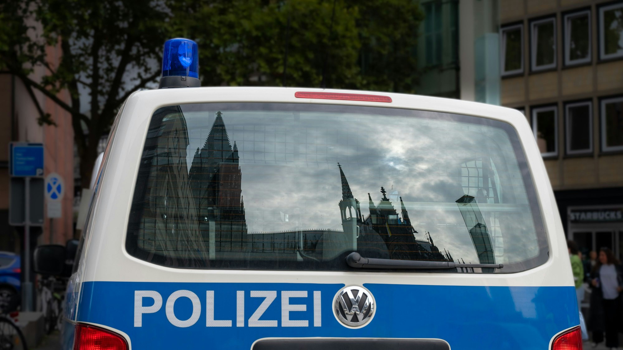 Der Dom spiegelt sich in einem Fenster eines Polizeifahrzeuges