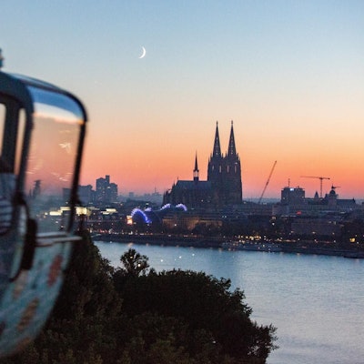Eine Gondel der Seilbahn vor dem Köln-Panorama in der Dämmerung