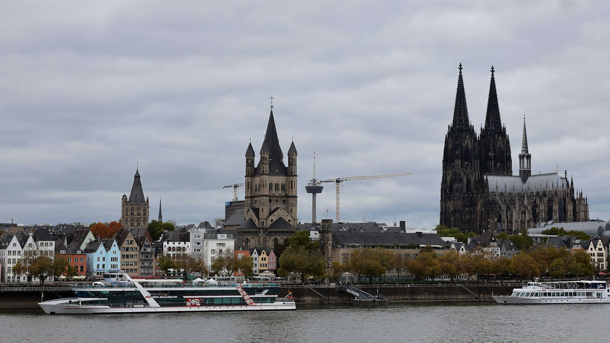 Blick auf das Panorama der Kölner Altstadt mit Groß St. Martin und Kölner Dom an einem verregneten Tag mit grauer Wolkendecke.