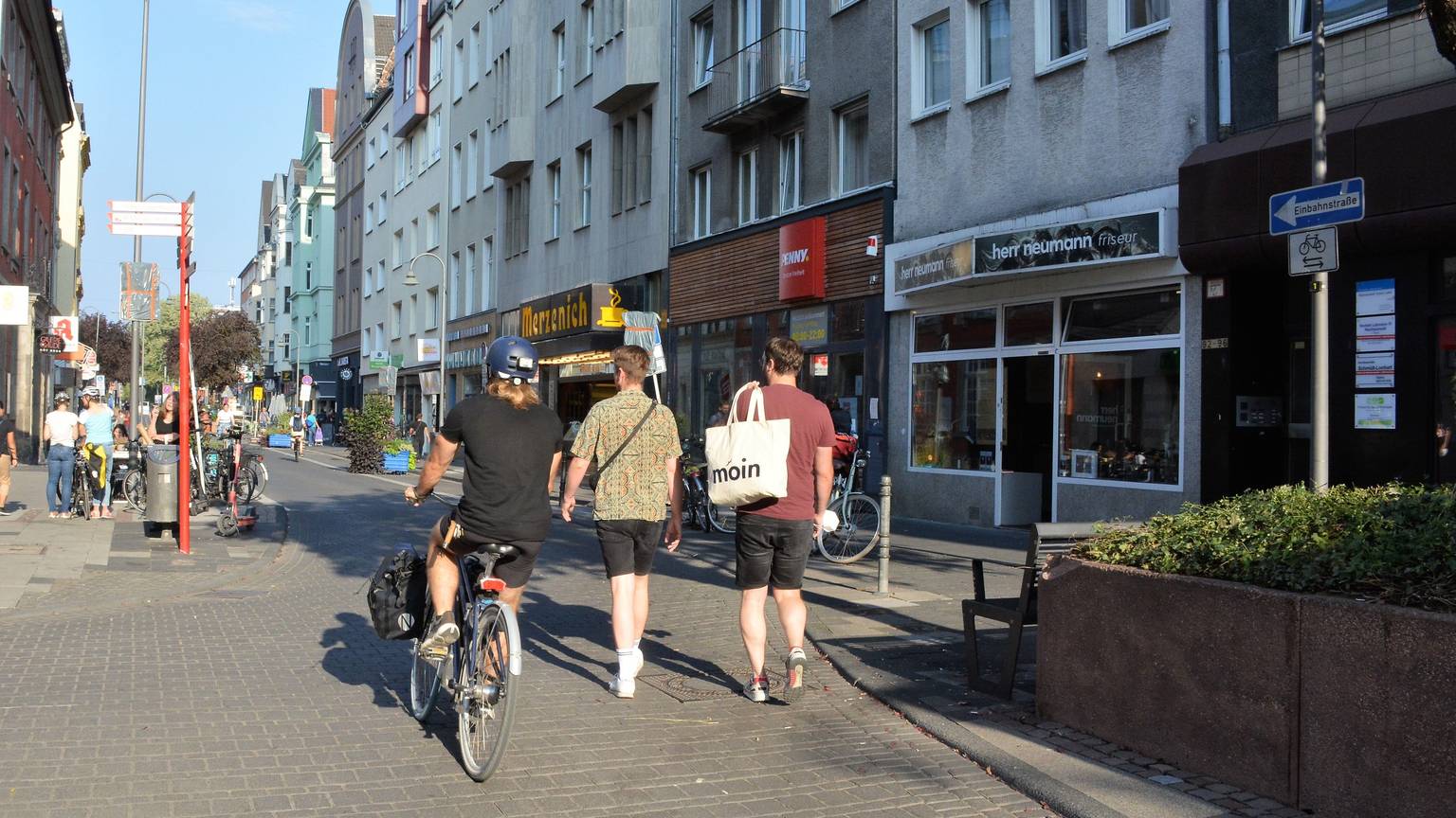 Ein Radfahrer und zwei Fußgänger laufen nebeneinander auf der Deutzer Freiheit.