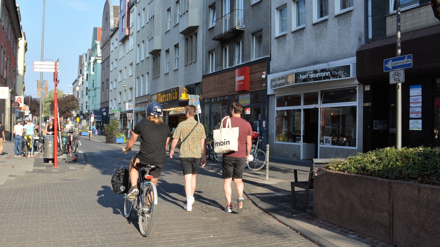 Ein Radfahrer und zwei Fußgänger laufen nebeneinander auf der Deutzer Freiheit.