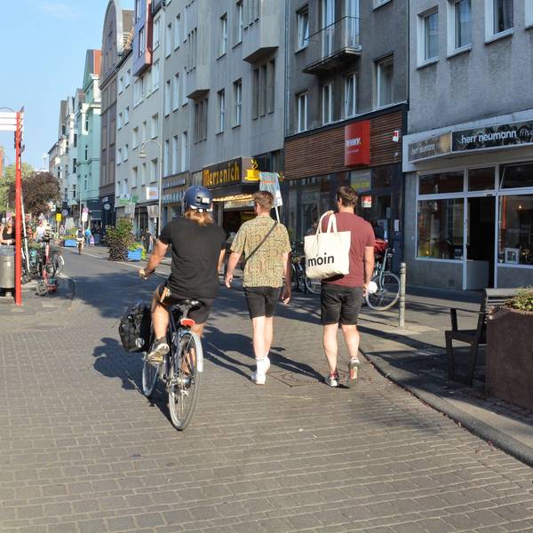 Ein Radfahrer und zwei Fußgänger laufen nebeneinander auf der Deutzer Freiheit.