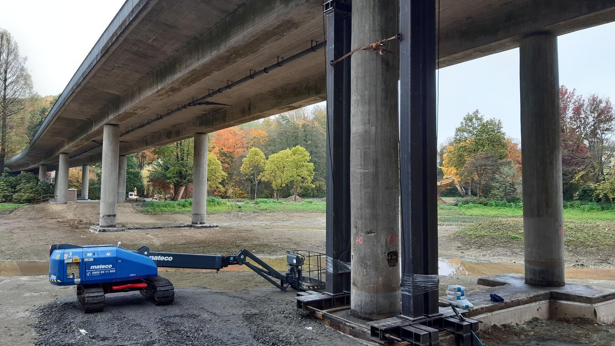 Eine Autobrücke mit Betonpfeilern ist von unten zusehen.
