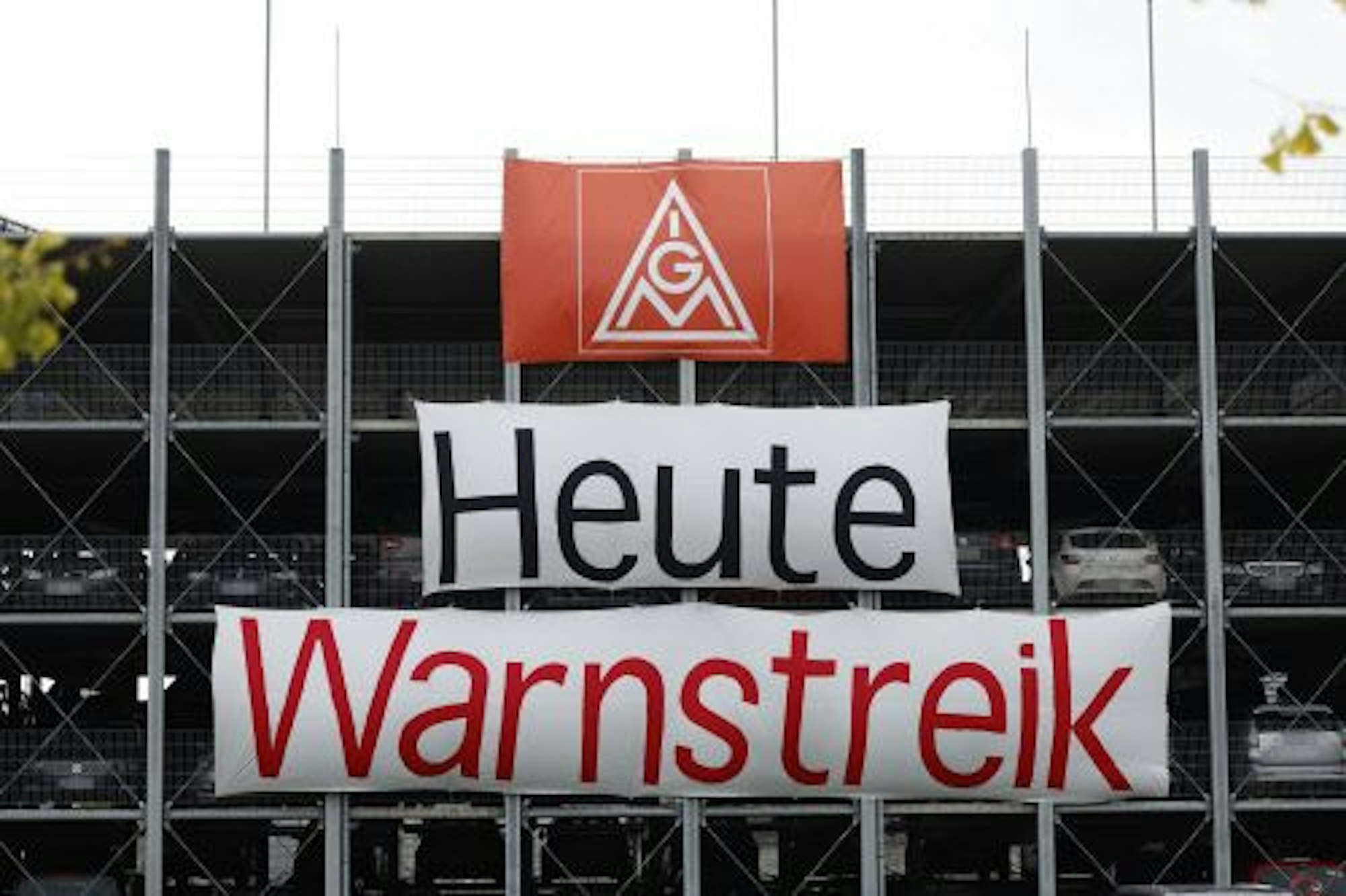 Am Zaun eines Betriebes hängt ein Transparent der IG Metall mit der Aufschrift "Heute Warnstreik"