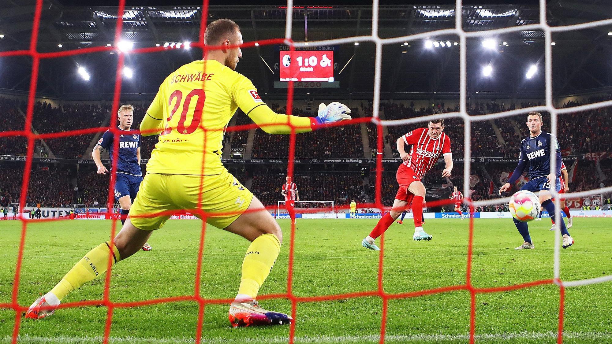 Von hinter dem Tor ist die Szene fotografiert, in der Freiburgs Michael Gregoritsch im roten Trikot per Kopfball das 2:0 für die Gastgeber besorgt. Im Vordergrund sieht man den Kölner Torwart Marvin Schwäbe im signalgelben Trikot, der den Ball nicht halten kann.