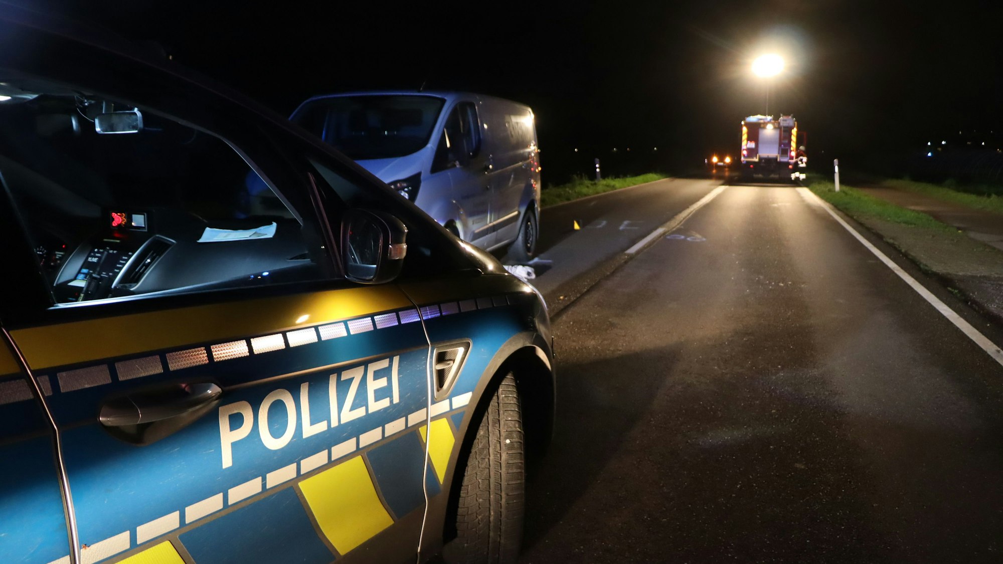 Ein Polizeiauto steht auf der Straße vor einem Transporter. Die Feuerwehr leuchtet die Unfallstelle aus.