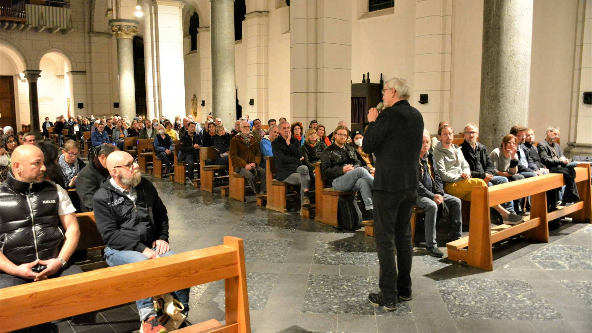 Bezirksbürgermeister Andreas Hupke steht im Mittelgang von St. Heribert und spricht zu den Gegnern und Befürwortern der aufofreien Deutzer Freiheit.