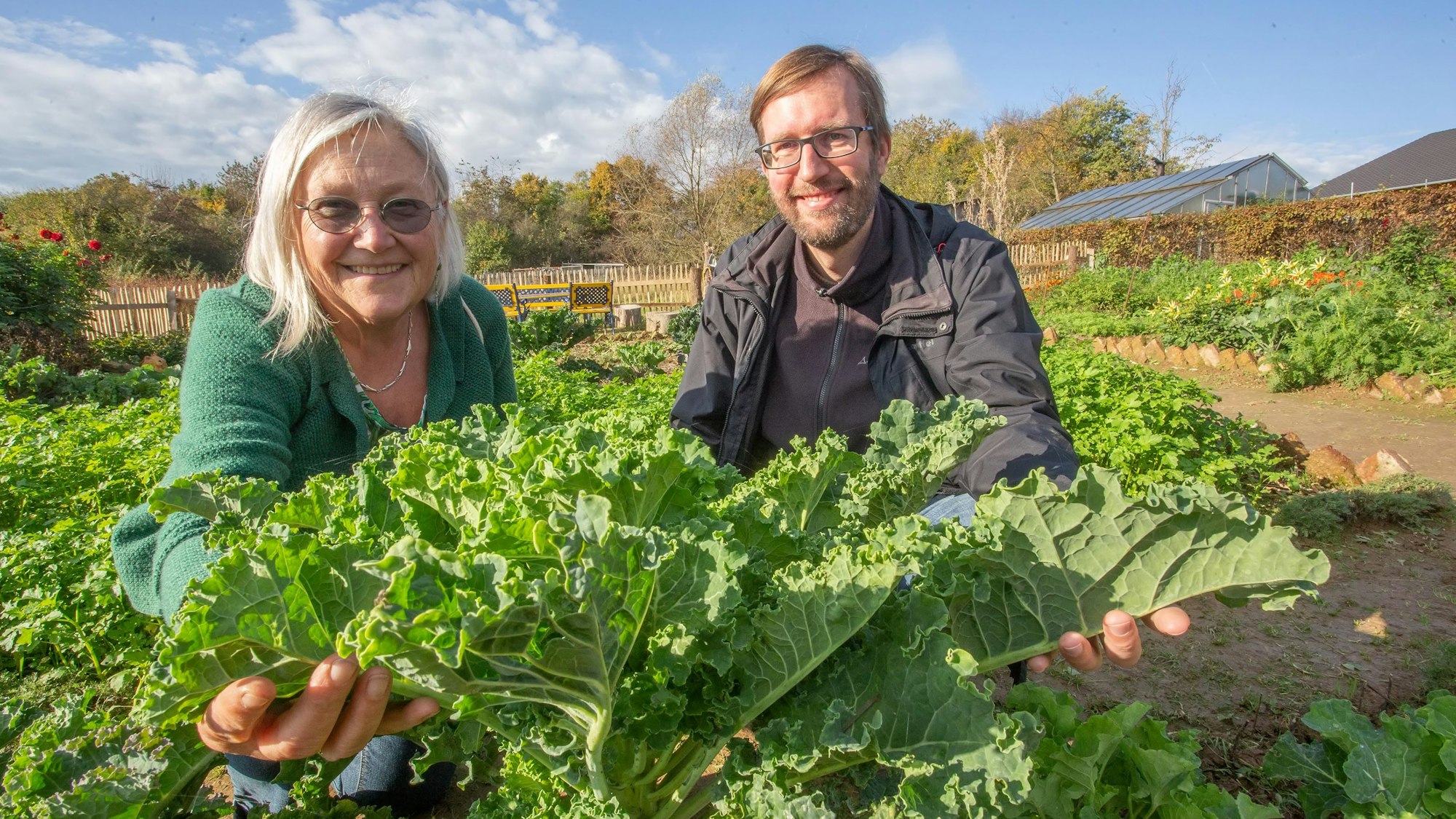 Marianne Frielingsdorf und Stephan Hahn halten Engkohl in die Kamera. Im Hintergrund ist ein Feld zu sehen.