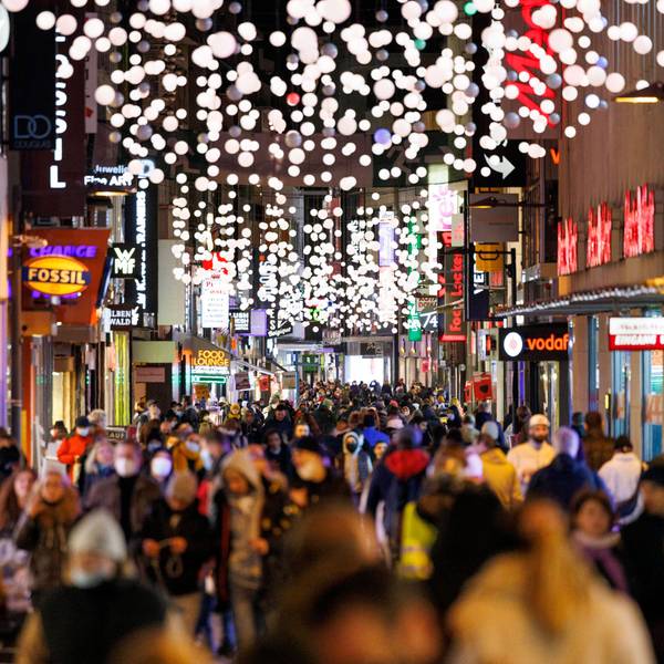Passanten streifen durch die von Weihnachtsbeleuchtung gesäumte Hohe Straße in Köln.