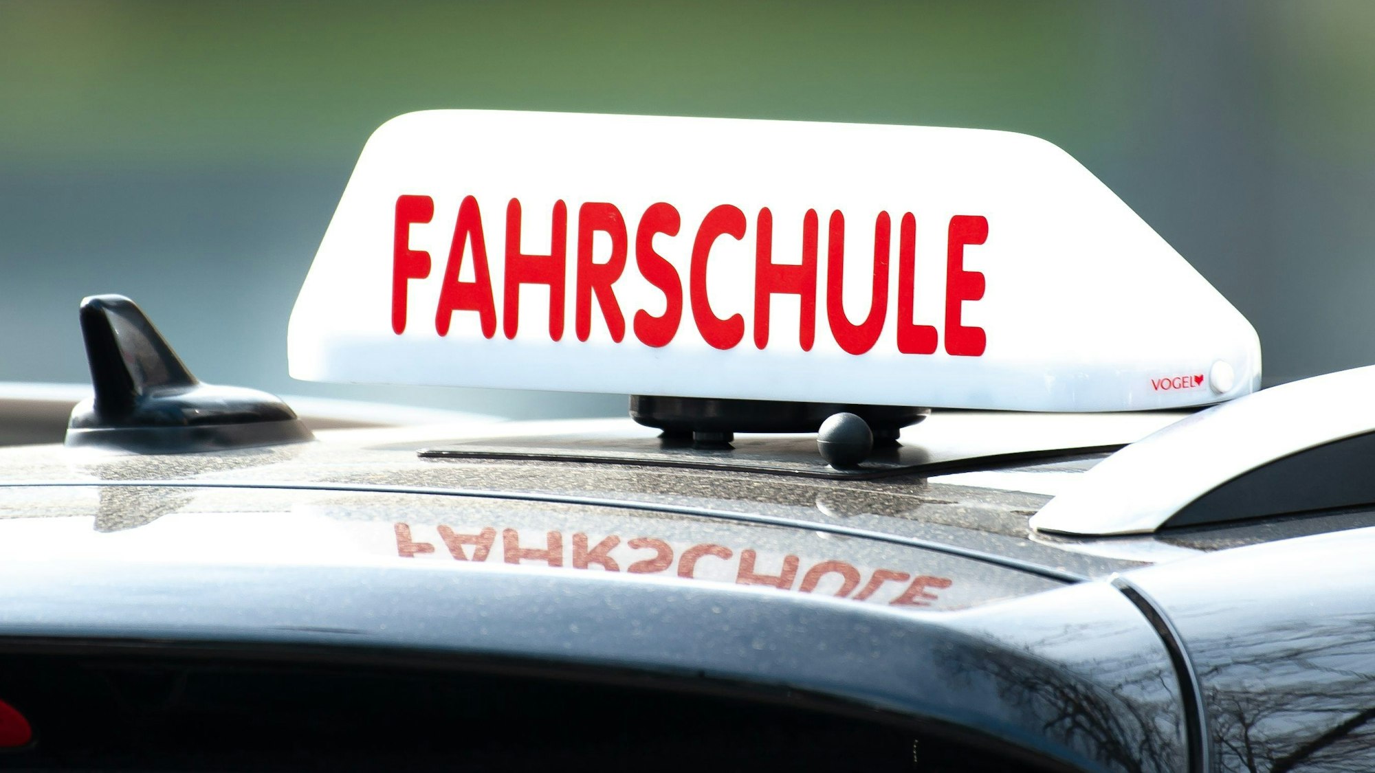 Ein Schild mit der Aufschrift «Fahrschule» ist auf einem Fahrschulauto befestigt.