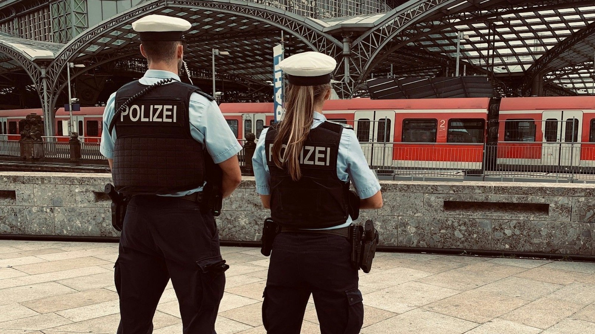 Ein Beamter (links) und eine Beamtin der Bundespolizei vor dem Kölner Hauptbahn