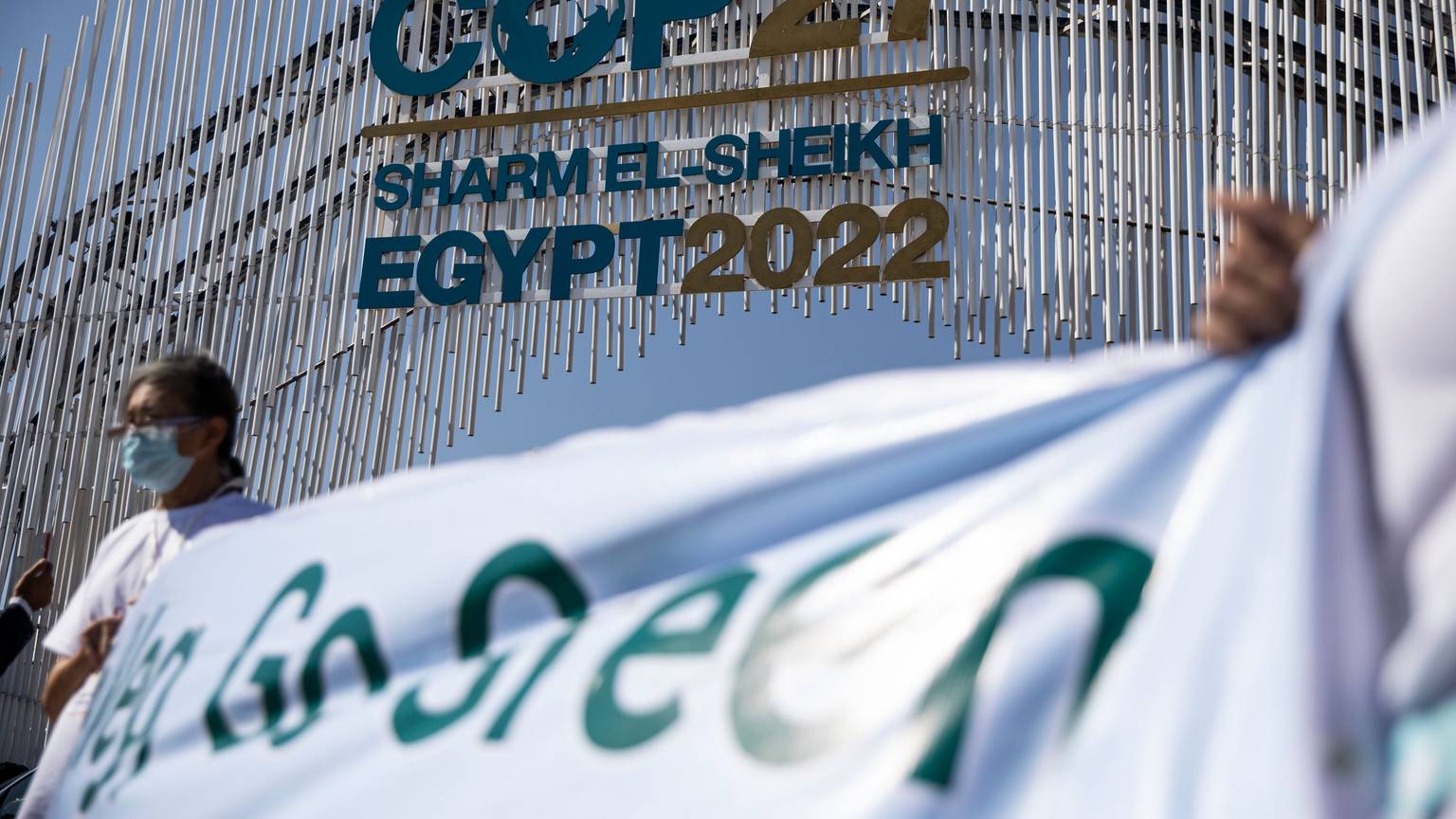 Umweltaktivisten halten ein Transparent vor dem Tor zur UN-Klimakonferenz COP27 im International Convention Center in Sharm El-Sheikh hoch.