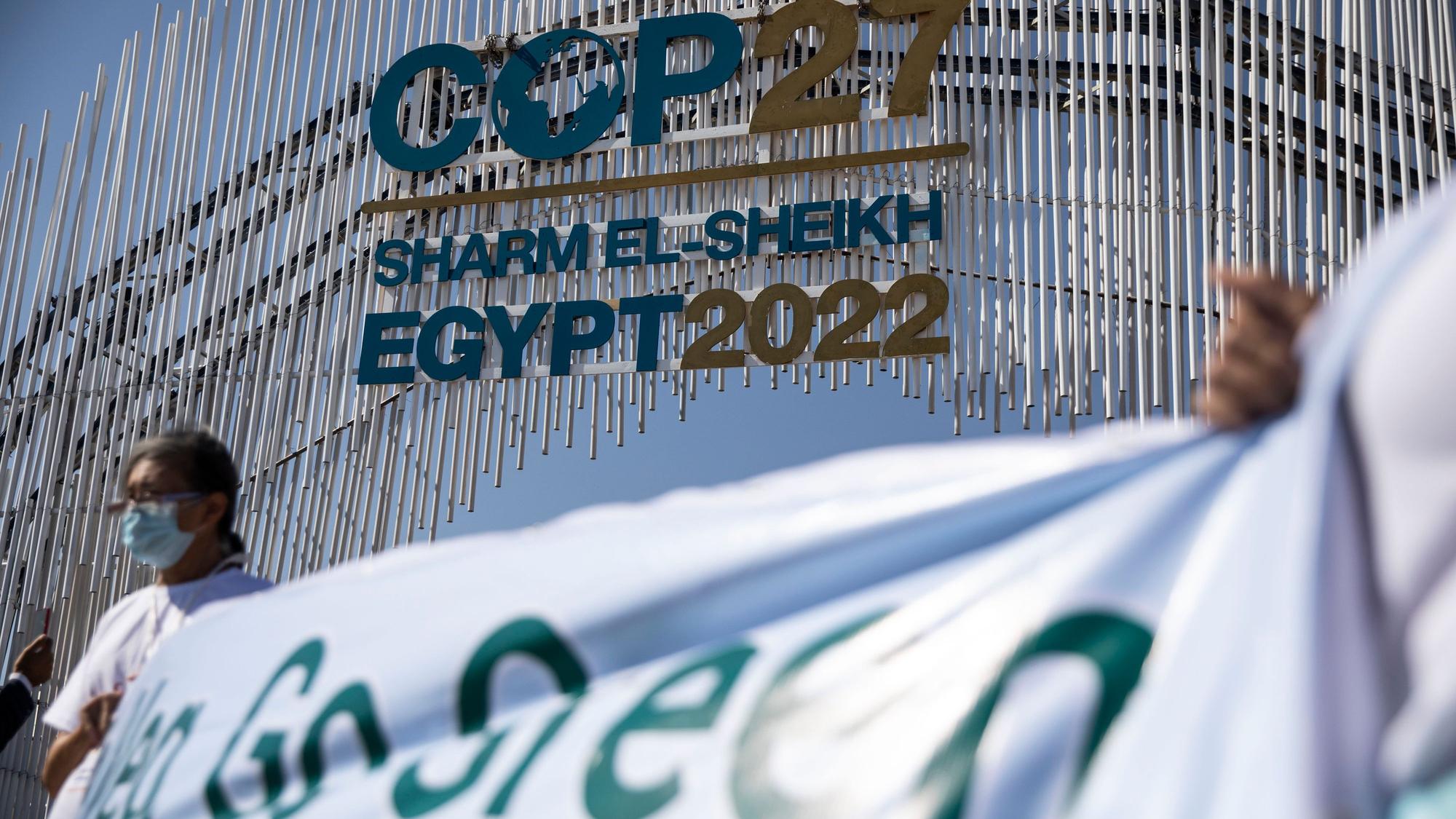 Umweltaktivisten halten ein Transparent vor dem Tor zur UN-Klimakonferenz COP27 im International Convention Center in Sharm El-Sheikh hoch.