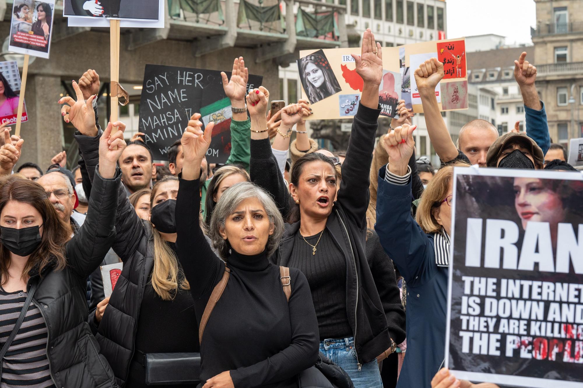 Iranerinnen und Iraner demonstrieren vor dem Dom. Sie strecken ihre Hände in die Luft und schauen wütend.