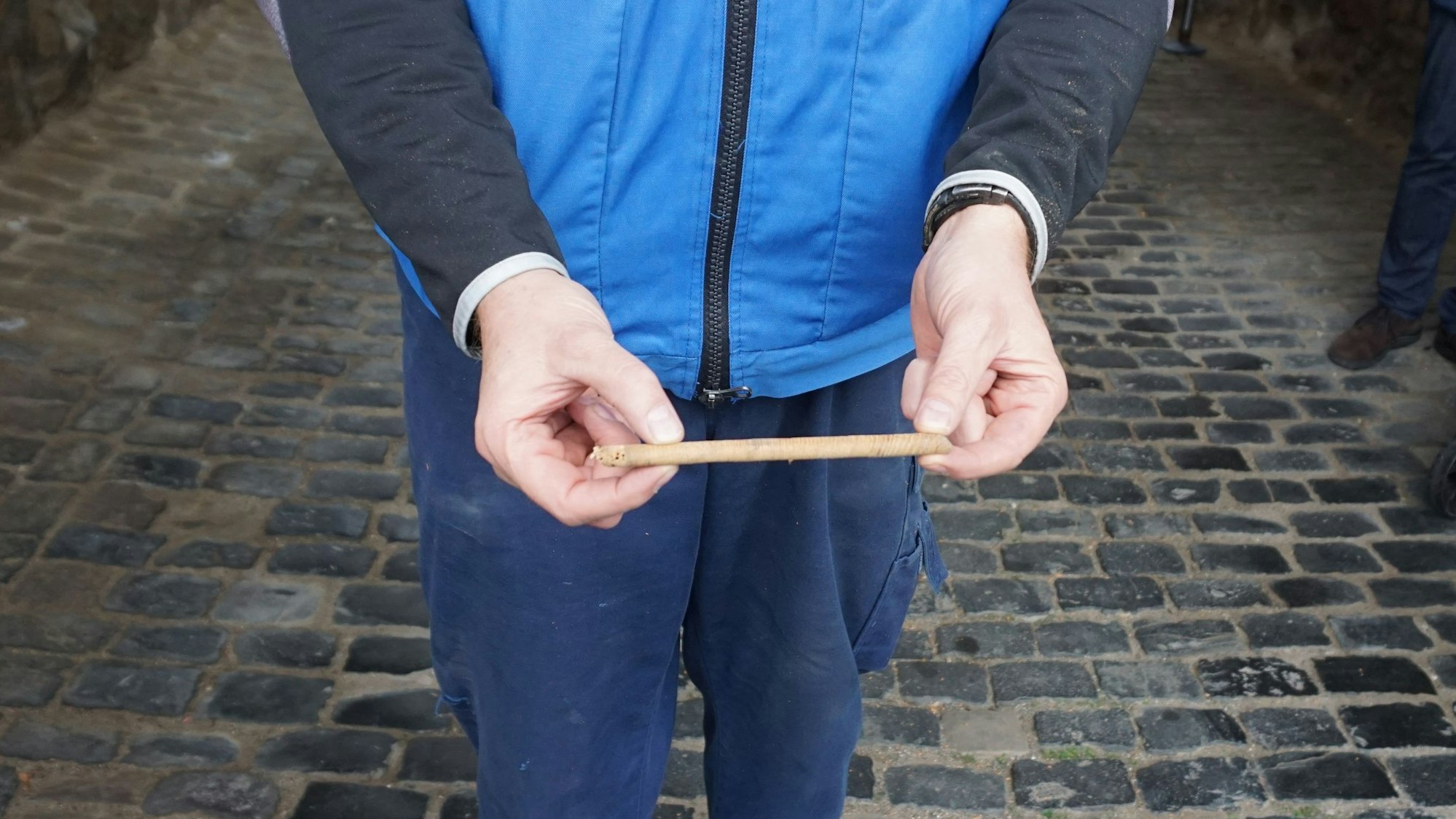 Ein Mann hält ein Stück eines Tors in eine Kamera. Er trägt eine blaue Jacke.