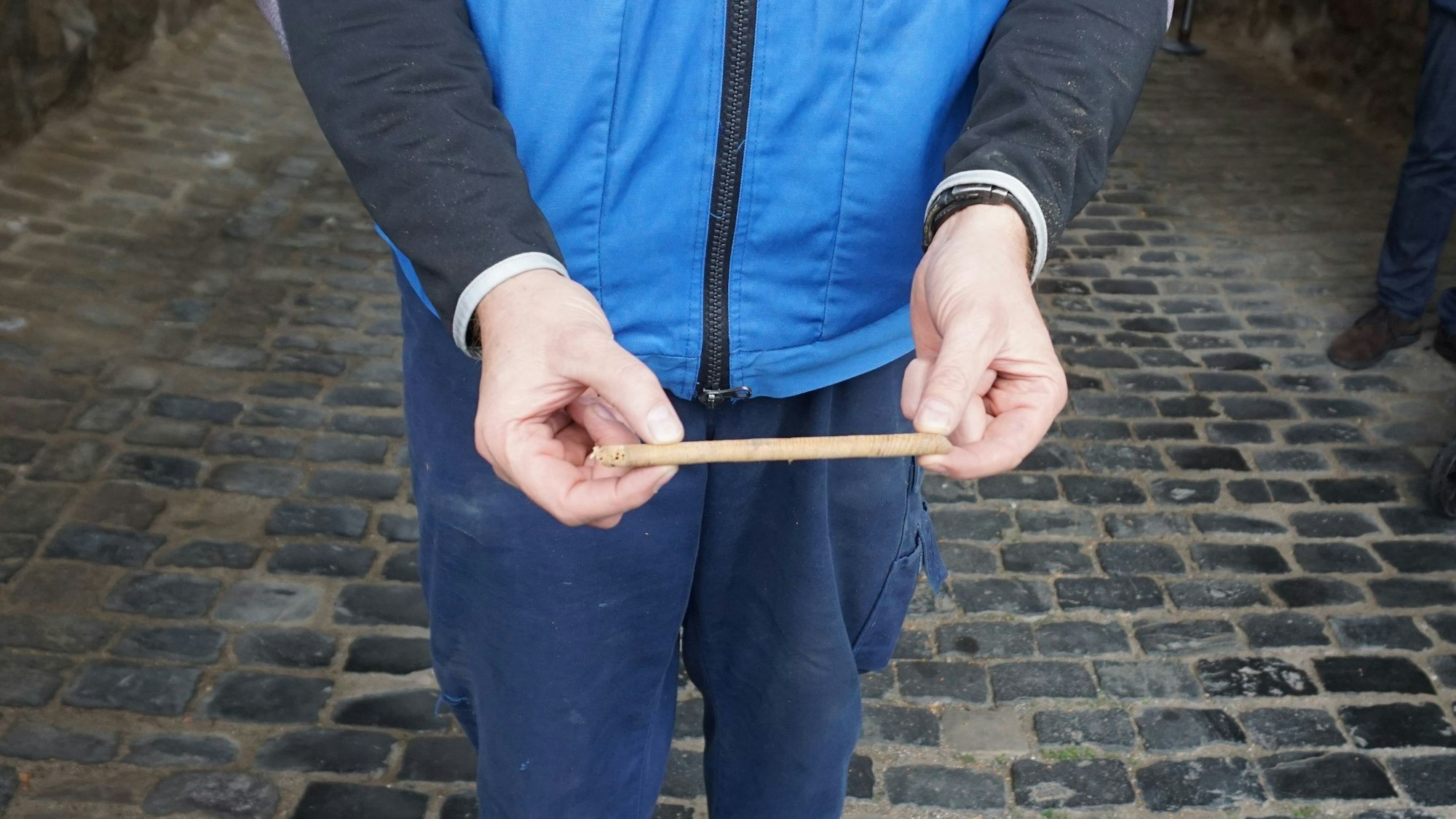 Ein Mann hält ein Stück eines Tors in eine Kamera. Er trägt eine blaue Jacke.