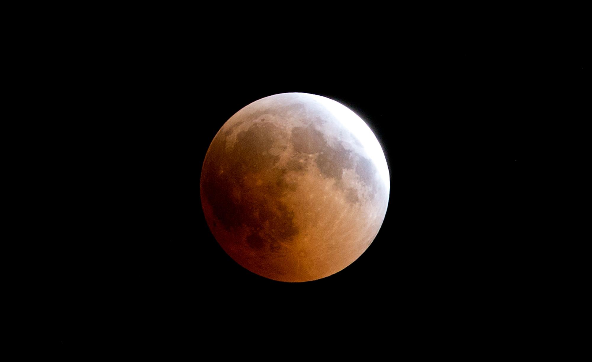 Ein rötlich gefärbter Vollmond ist am Himmel zu sehen.