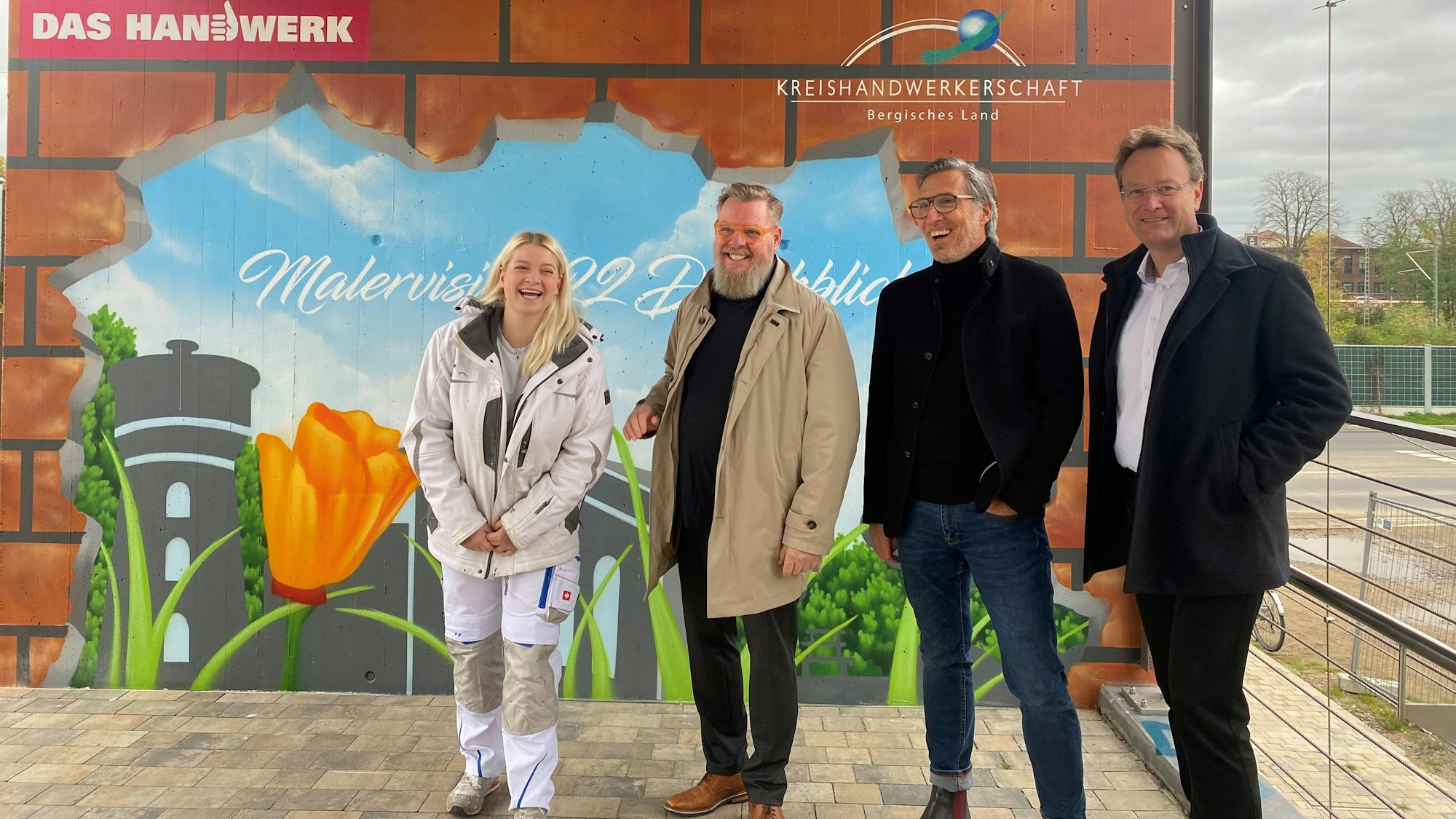 Ein Graffito an der Säule der Campusbrücke mit den fröhlichen Beteiligten davor.