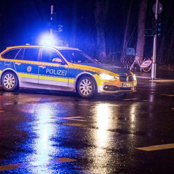 Ein Polizeifahrzeug steht auf einer Kreuzung bei Nacht im Regen.