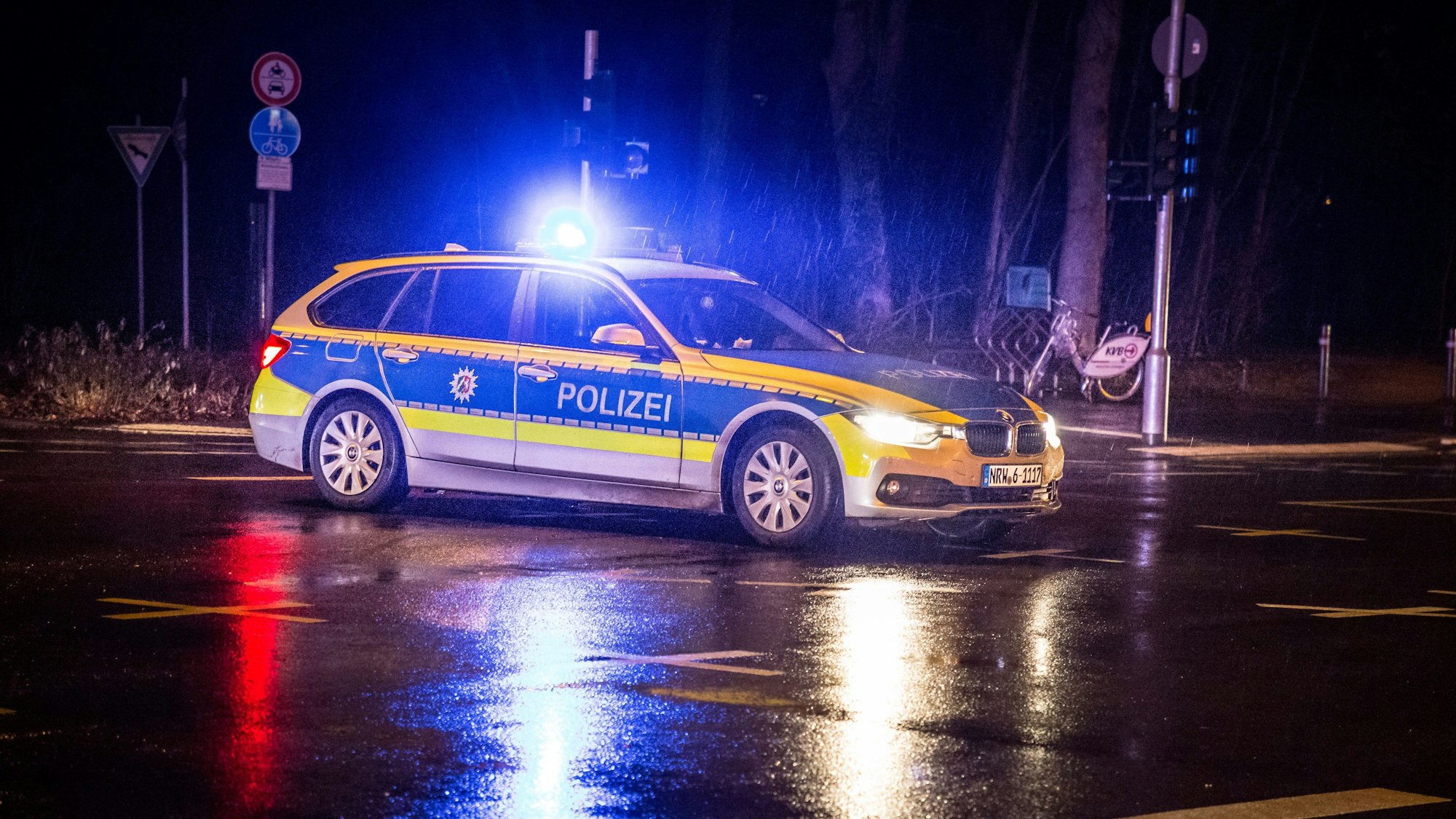 Ein Polizeifahrzeug steht auf einer Kreuzung bei Nacht im Regen.
