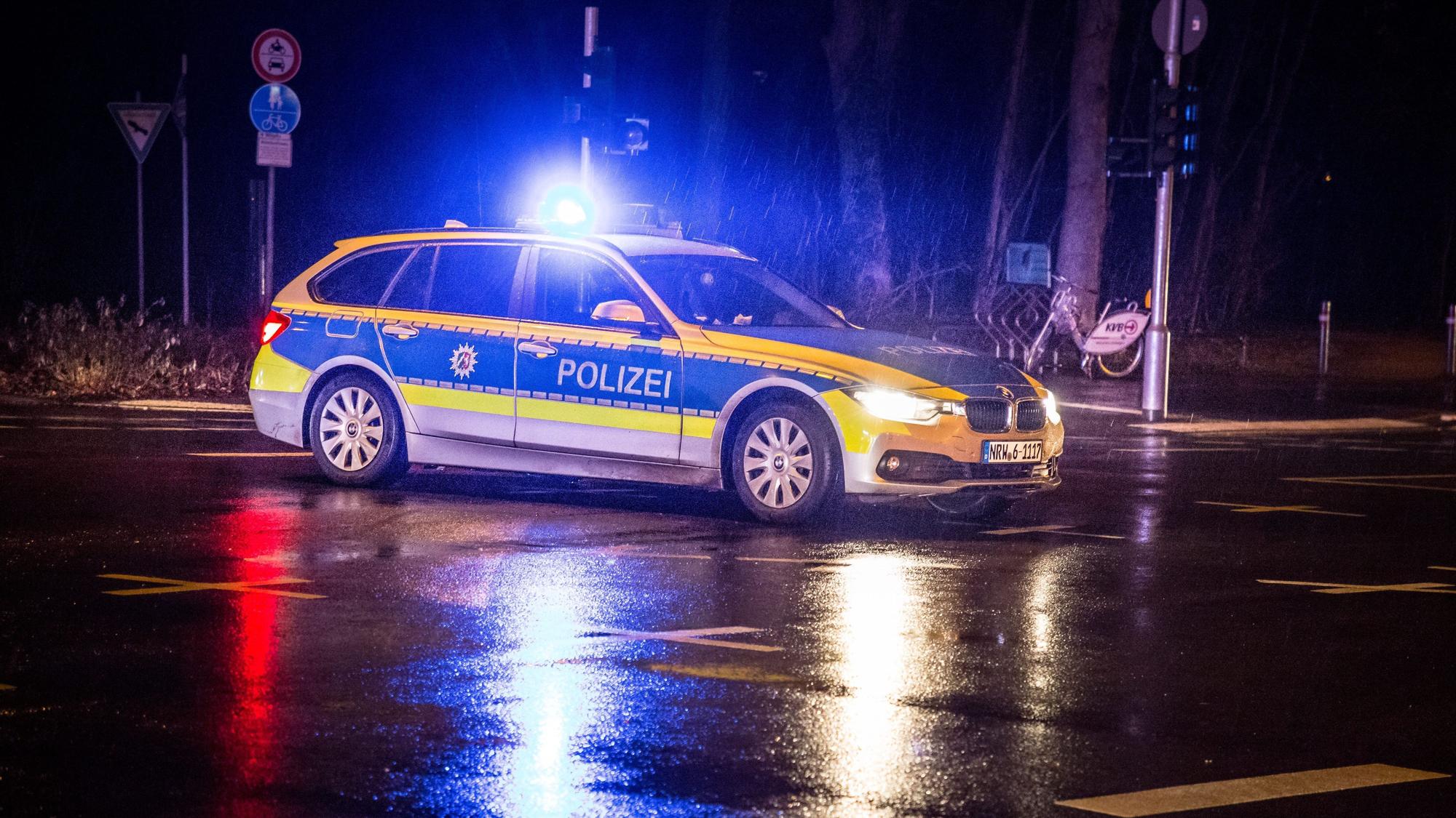 Ein Polizeiwagen steht mit Blaulicht nachts auf einer Straße.