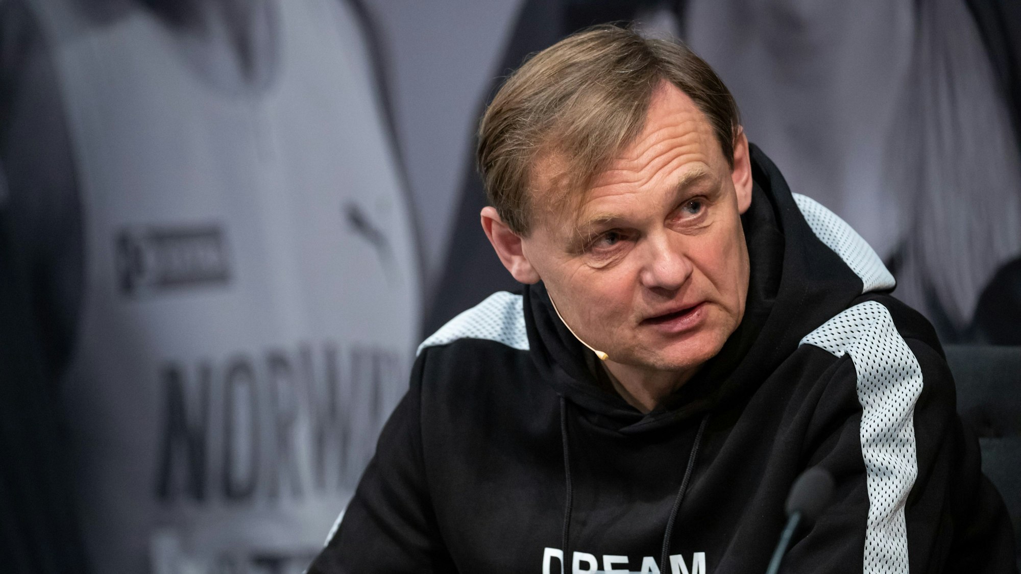 Björn Gulden bei einer Pressekonferenz. Er trägt einen Pullover von Puma.