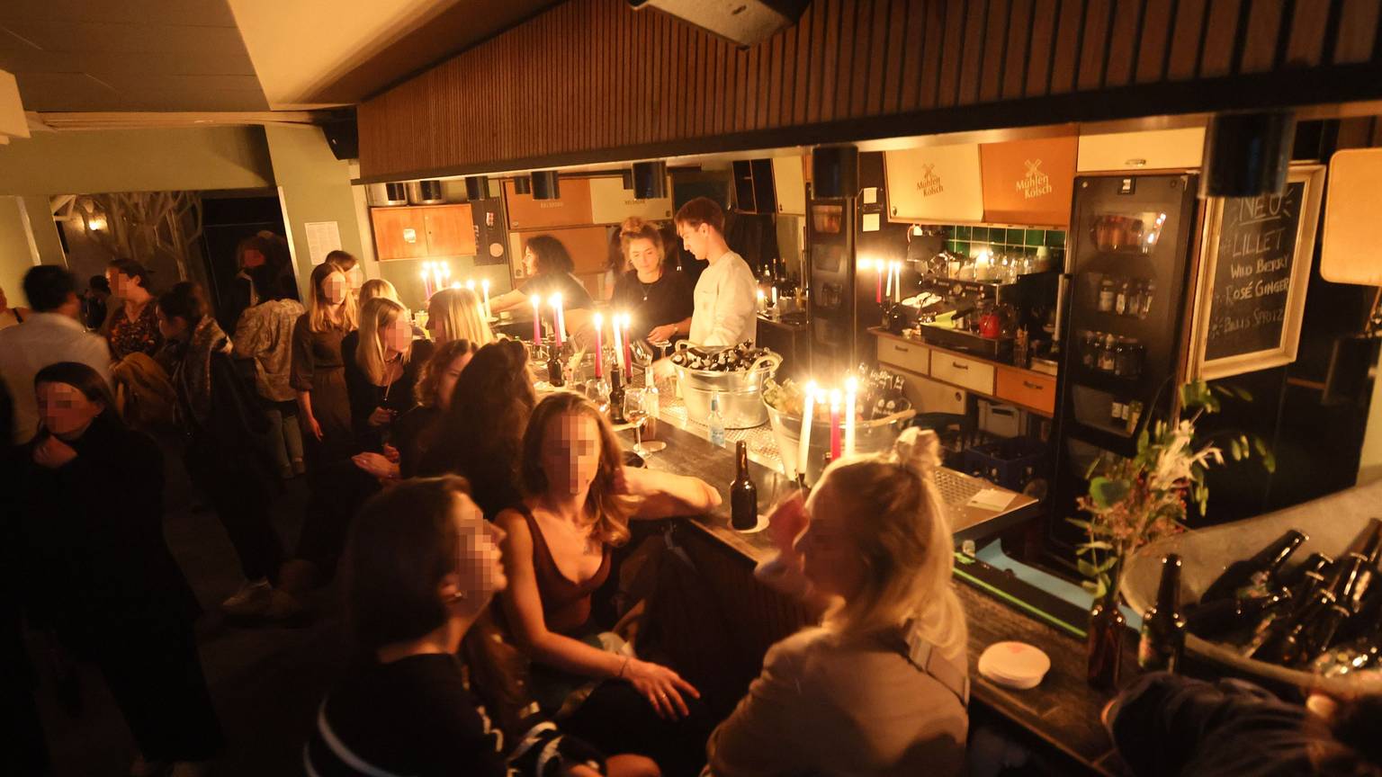 In der Kölner Bar Wohngemeinschaft sitzen Gäste bei Kerzenschein an der Theke.