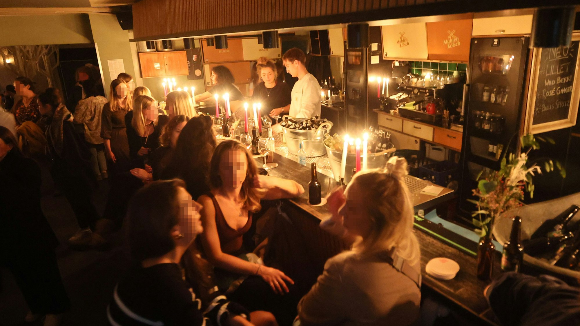 In der Kölner Bar Wohngemeinschaft sitzen Gäste bei Kerzenschein an der Theke.