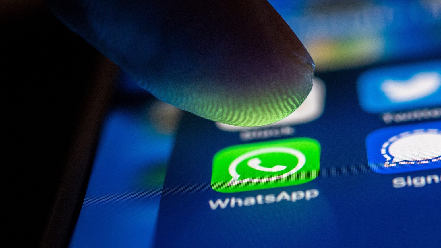 Ein Finger tippt auf dem Bildschirm eines Smartphones auf das Whatsapp-Icon.