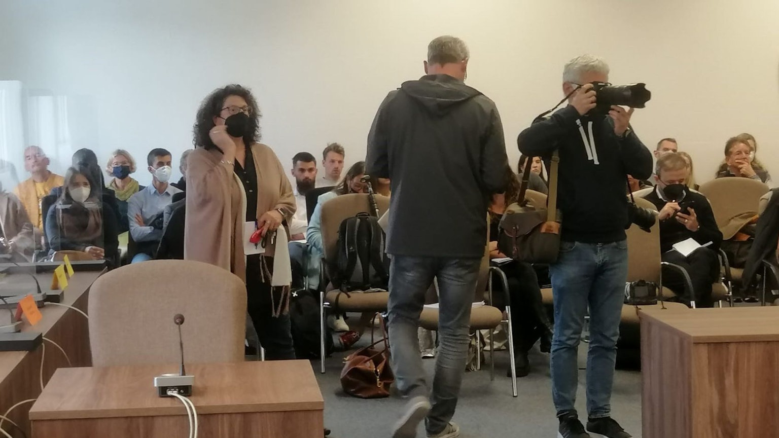 In dem Gerichtssaal sitzen viele Pressevertreter und Zuschauer.