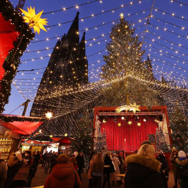 Besucher gehen über den Weihnachtsmarkt auf dem Roncalliplatz am Dom.