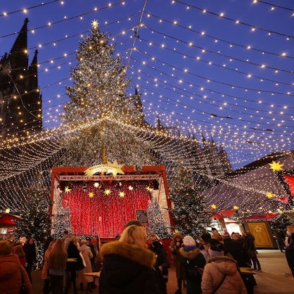 Besucher gehen über den Weihnachtsmarkt auf dem Roncalliplatz am Dom.