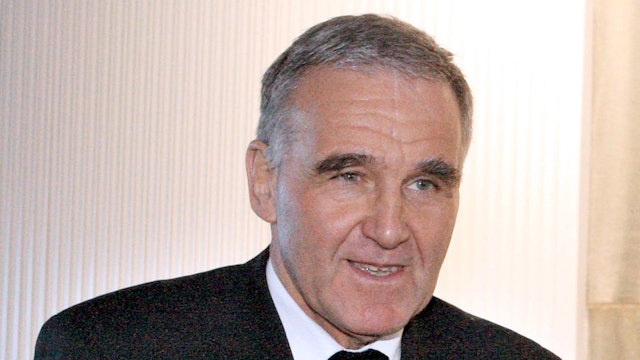 Weihbischof Johannes Bündgens vor weißem Hintergrund. Er guckt an der Kamera vorbei und lächelt leicht.