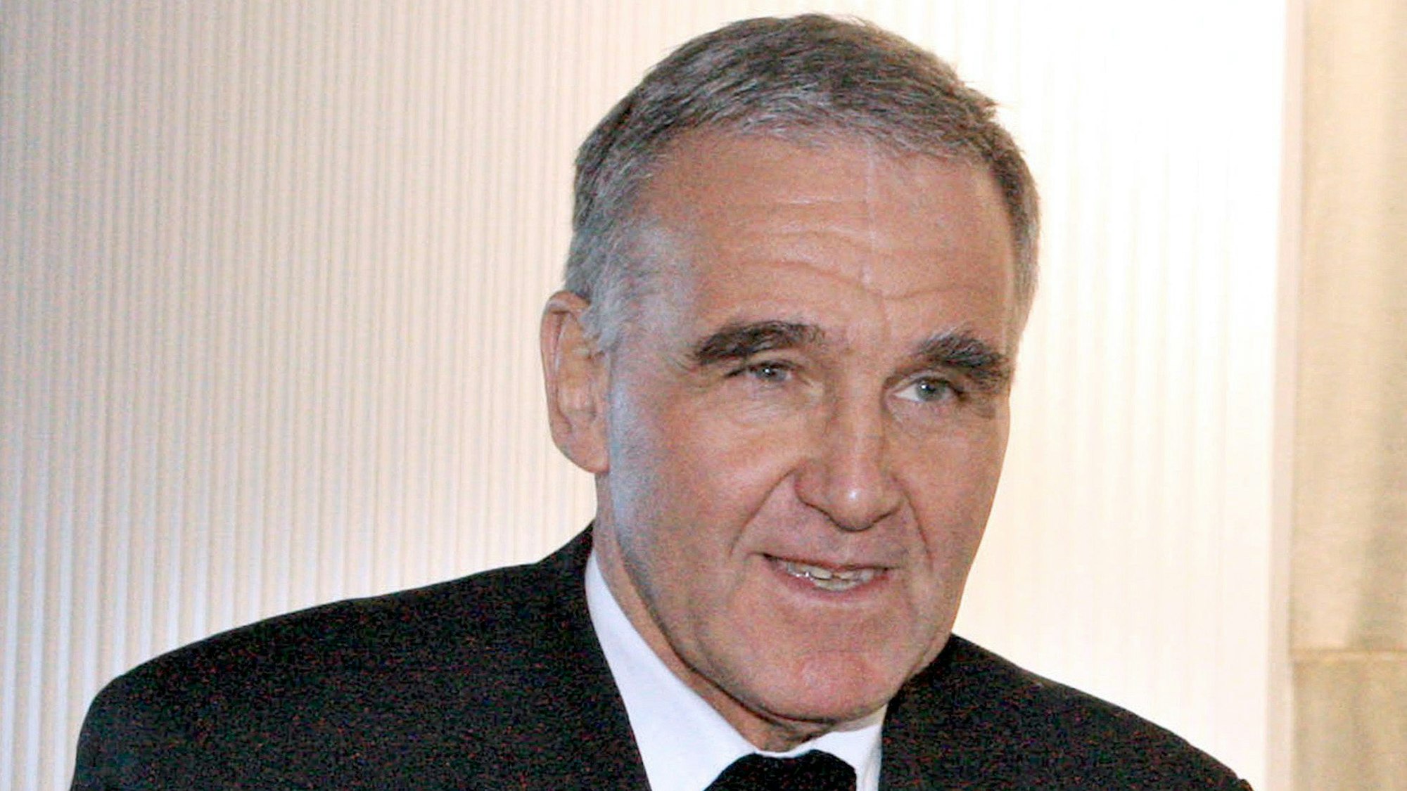 Weihbischof Johannes Bündgens vor weißem Hintergrund. Er guckt an der Kamera vorbei und lächelt leicht.