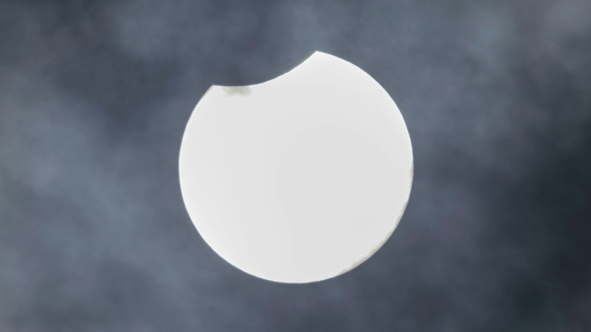 Der Mond verdeckt einen kleinen Teil der Sonne über Köln.