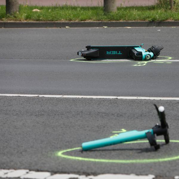 Auf der Straße liegen Wrackteile eines E-Scooters auf dem Asphalt