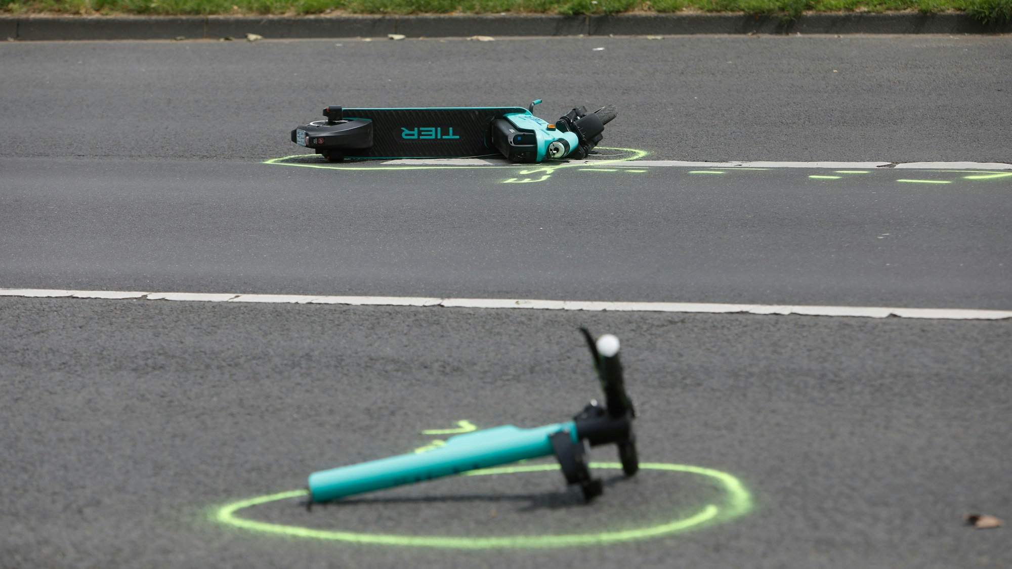 Auf der Straße liegen Wrackteile eines E-Scooters auf dem Asphalt