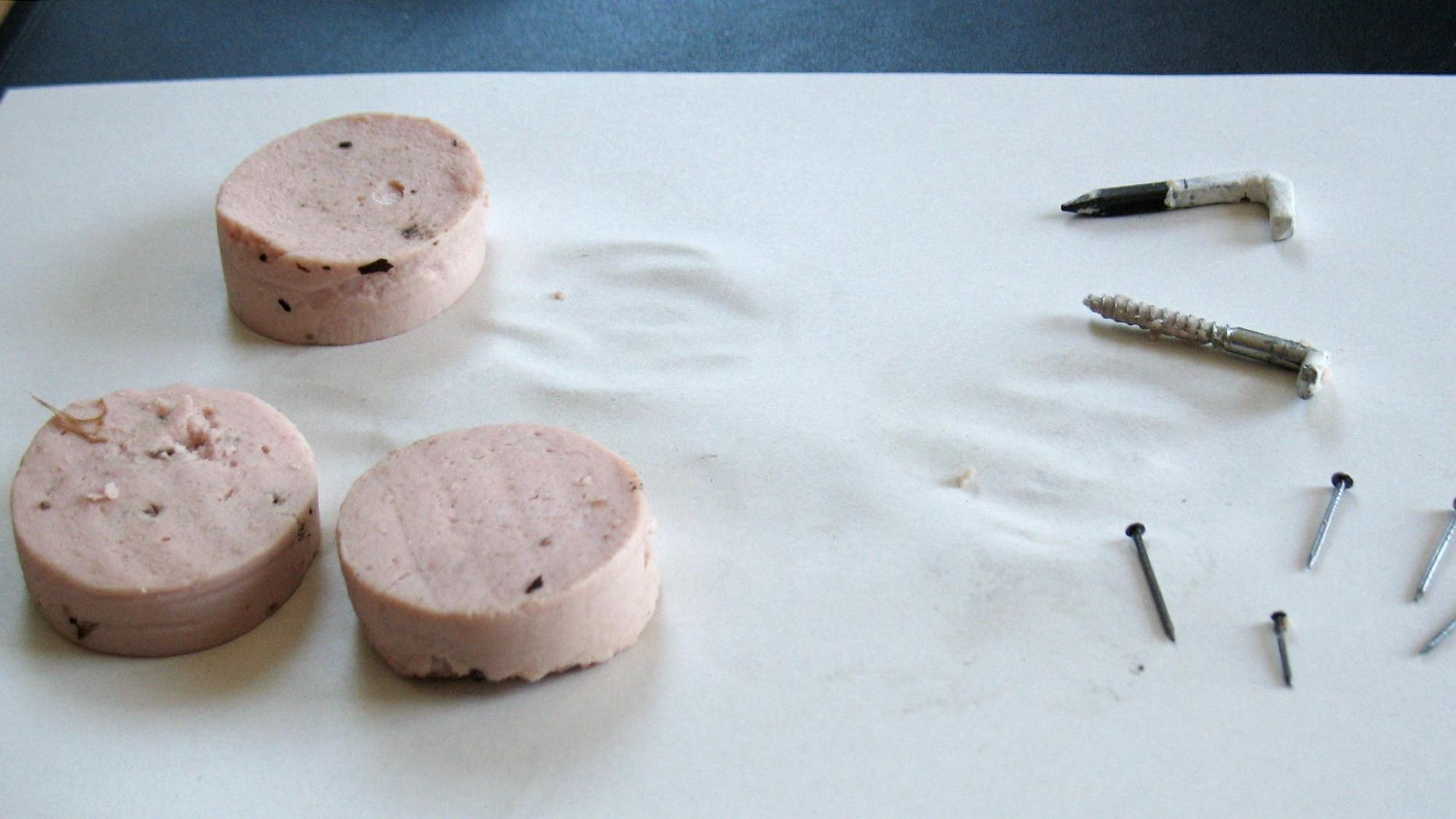 Drei Hundeköder, die mit verschiedenen Arten von Schrauben und Nägeln versetzt sind. (Symbolbild)