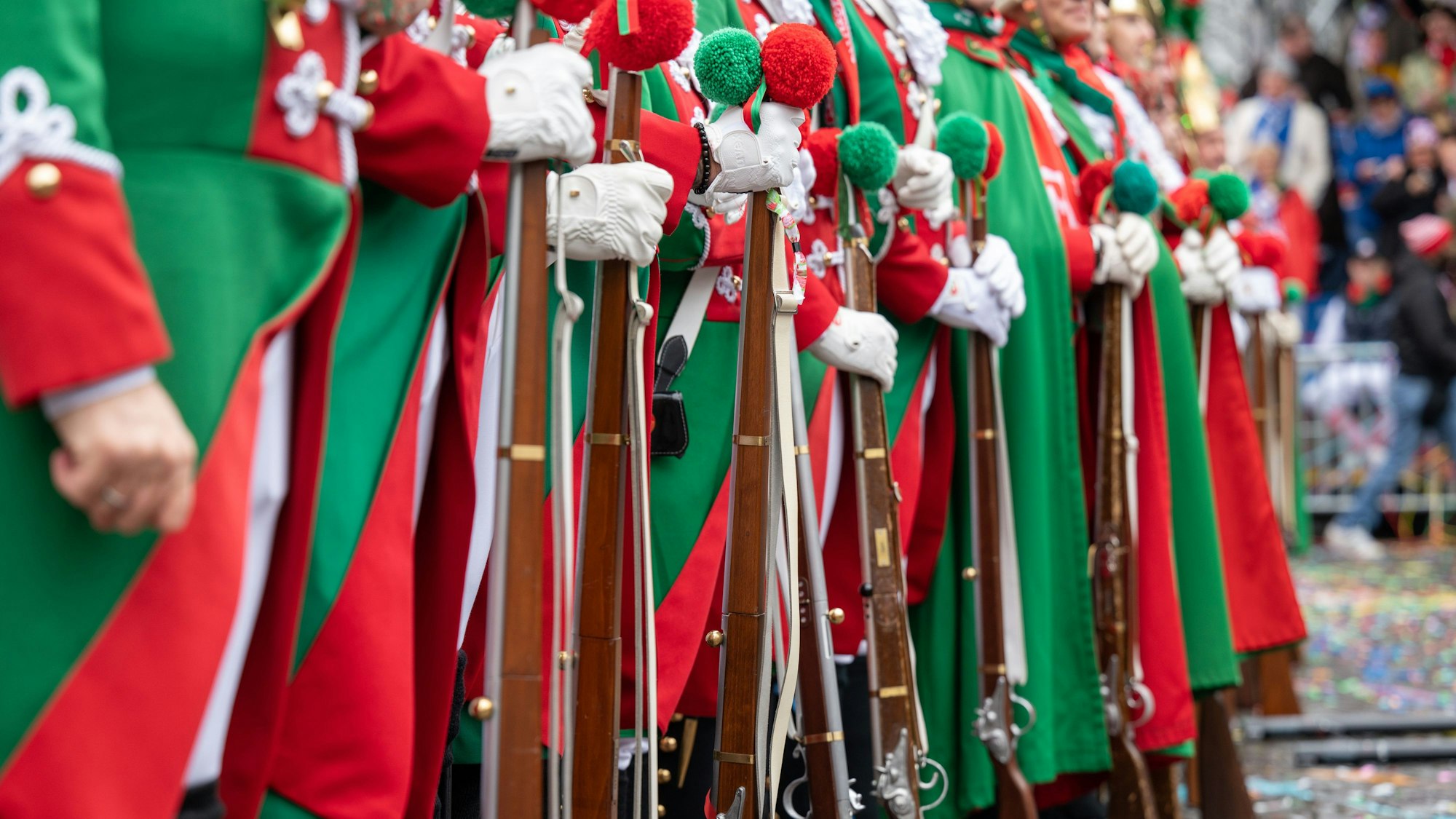24.02.2022, Köln: Gardisten der Altstädter mit Holzgewehren an Weiberfastnacht in soldatischen Uniformen. Trotz des kriegerischen Einmarschs Russlands in die Ukraine an diesem Tag feiern Menschen die Karnevalseröffnug. Foto: Uwe Weiser