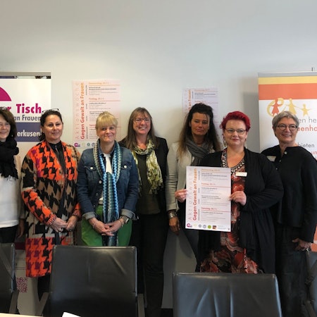 Nebeneinander stehen acht Frauen (von rechts nach links): Roswitha Kneip (Frauenring), Jaqueline Tombeux (Frauenhaus), Christiane Meikert (Beratungsstelle gegen sexualisierte Gewalt), Andrea Frewer (Beratungsstelle gegen sexualisierte Gewalt), Cornelia Richrath (Gleichstellungsbüro), Vera Hahn (Zonta Club), Manuela Krewitt-Herrmann (Frauenring), Nina Schwimmbeck