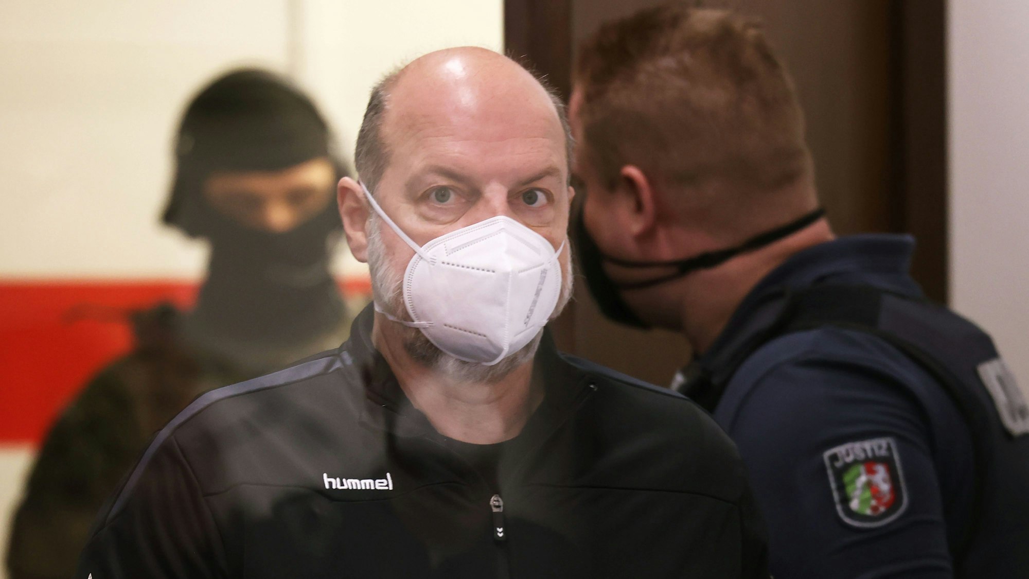 Der Angeklagte Thomas Drach beim Prozess im Landgericht. Rechts ein Justiz-Wachtmeister, im Hintergrund ein SEK-Beamter.