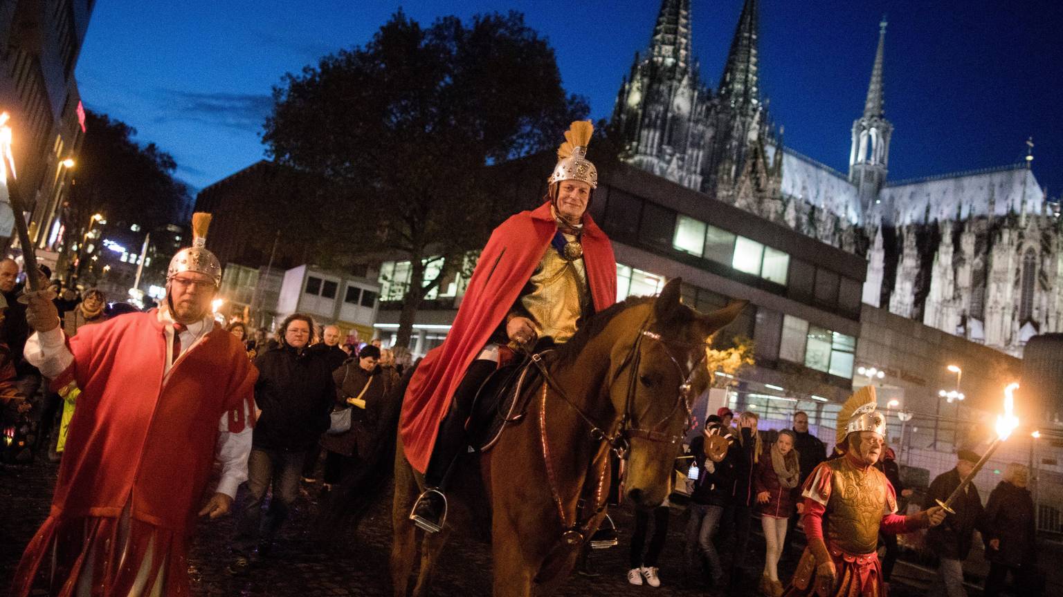 Der „Heilige Sankt Martin“ reitet bei einem Martinszug am Dom vorbei.