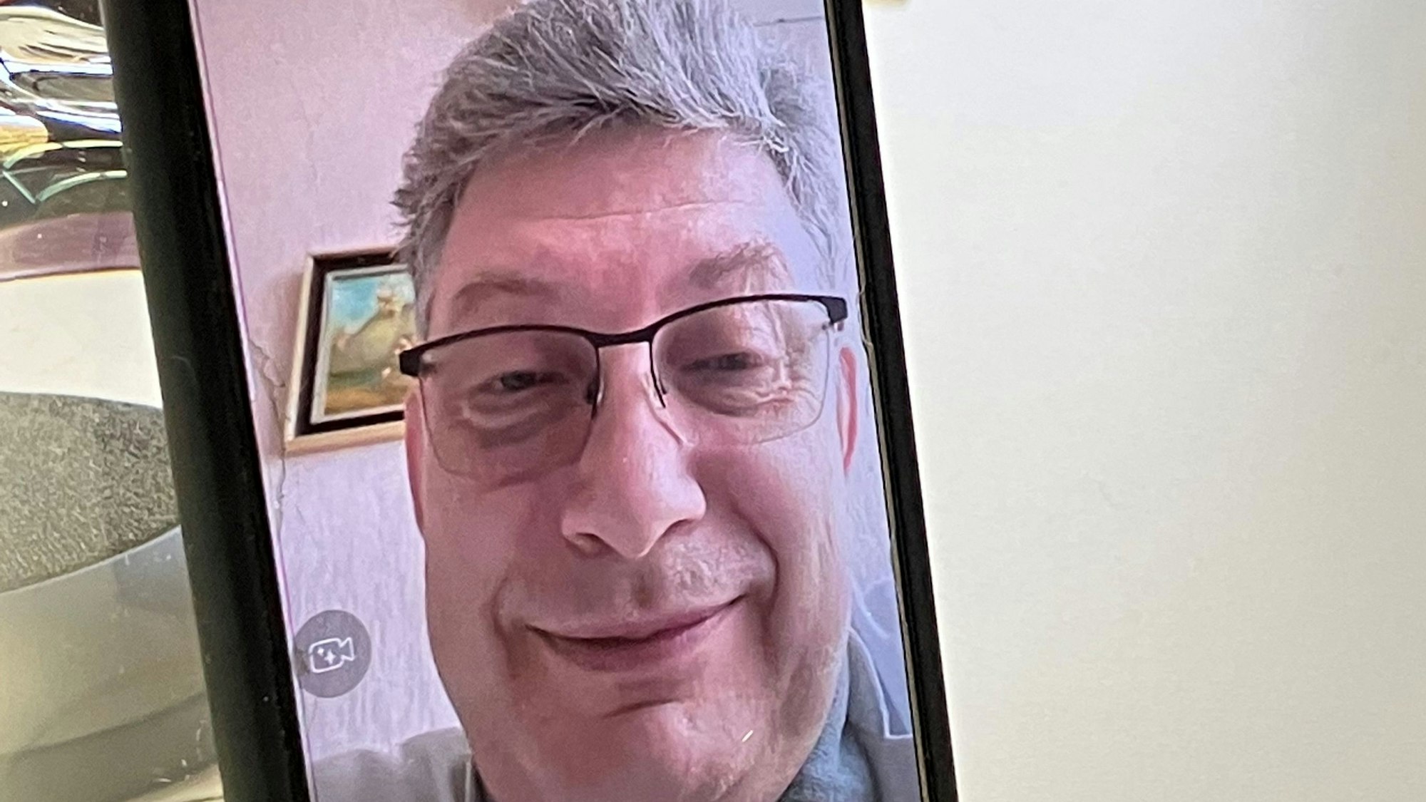 Dr. Vitaliy P., Arzt aus Charkiw, ist im Rahmen eines Videotelefonats auf einem Handybildschirm zu sehen.