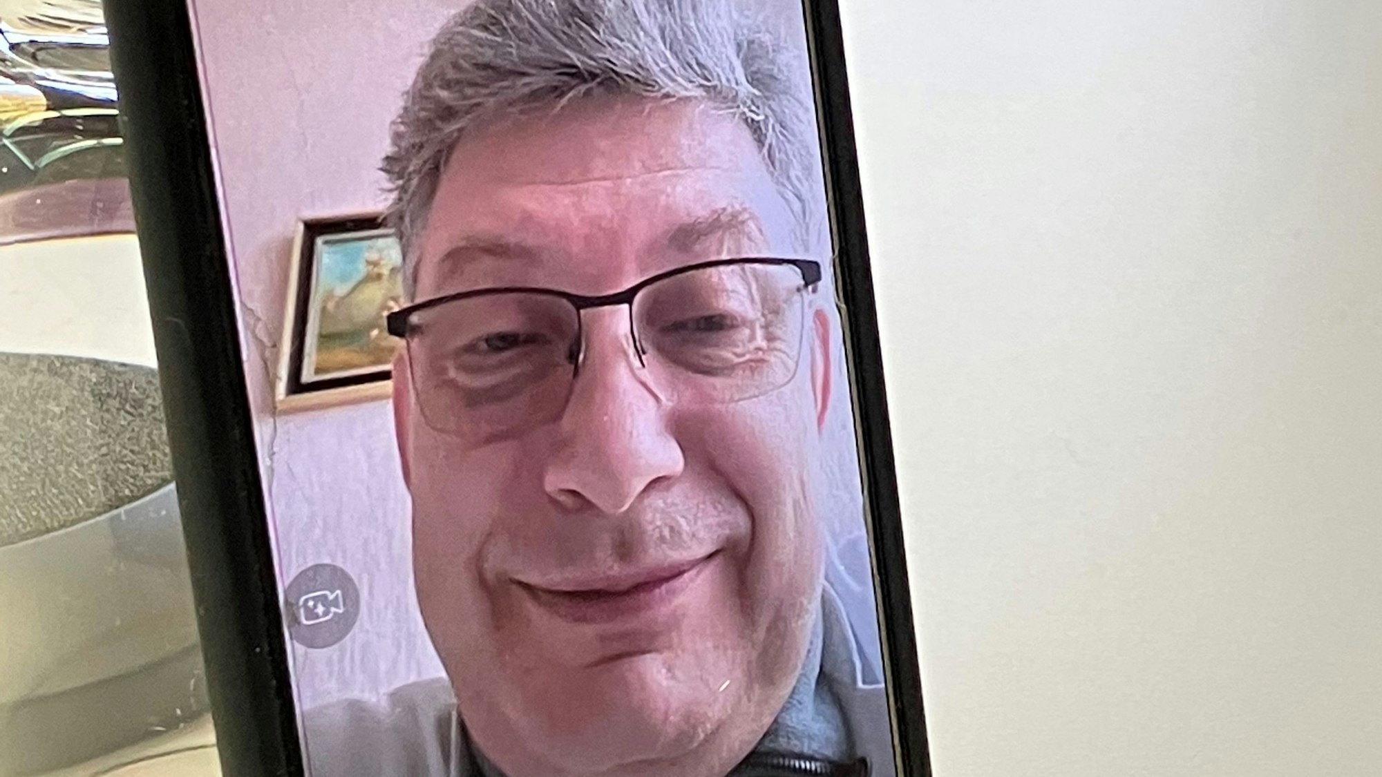 Dr. Vitaliy P., Arzt aus Charkiw, ist im Rahmen eines Videotelefonats auf einem Handybildschirm zu sehen.