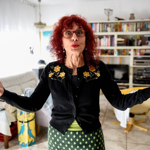 Shulamit Grohmann steht in ihrem Wohnzimmer, spitzt den Mund und hebt die Hände.