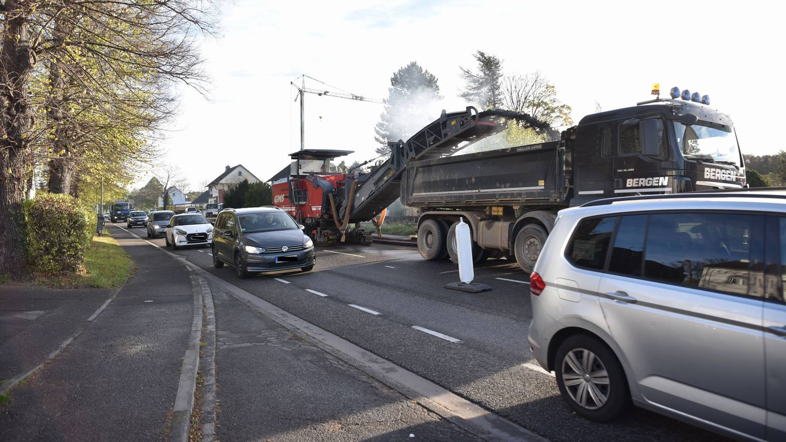 Viele Autos fahren dicht an den Baustellenfahrzeugen auf der B266 vorbei.