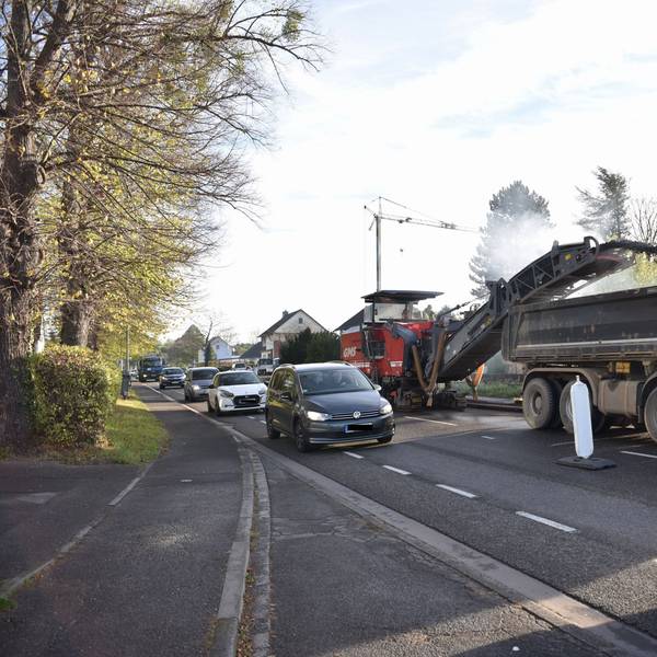 Viele Autos fahren dicht an den Baustellenfahrzeugen auf der B266 vorbei.